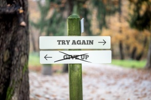 Signboard with two signs saying - Try again - Give up - pointing